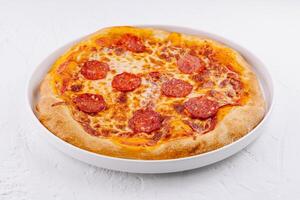 Freshly baked pepperoni pizza on white plate photo