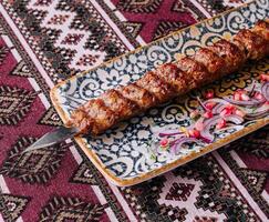 Traditional grilled kebab on ornate plate photo