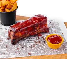 Succulent bbq pork ribs with dipping sauce and wedges photo
