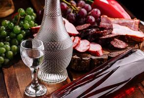 Luxurious vodka and charcuterie spread on wooden table photo