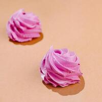 Pastel pink meringue swirls on peach background photo