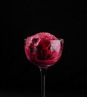 Elegant glass of strawberry sorbet on black background photo