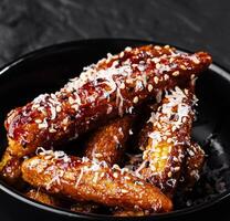 Honey glazed chicken wings in black bowl photo