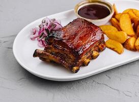 Succulent bbq pork ribs with wedges and sauce photo