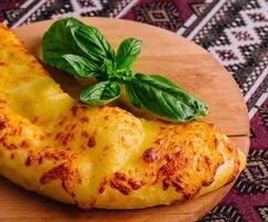 Georgian cheese bread khachapuri on wooden board photo