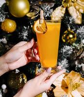Festive holiday drink in hand by christmas tree photo