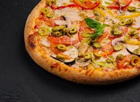 Freshly baked vegetable pizza on black background photo