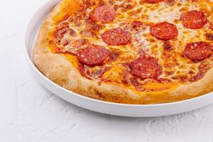 Freshly baked pepperoni pizza on white plate photo