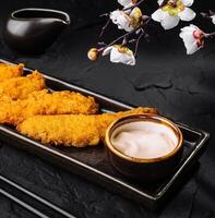 Crispy breaded shrimp with dipping sauce and cherry blossoms photo