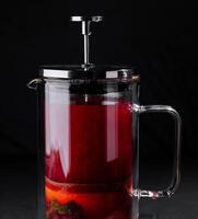 Fruit infused tea in french press on dark background photo