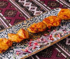 Traditional marinated grilled chicken skewers on ornate plate photo