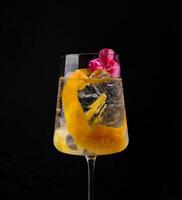 Exotic cocktail with orange twist and flowers photo