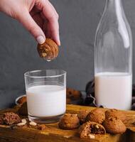 Hand dipping cookie in milk glass photo