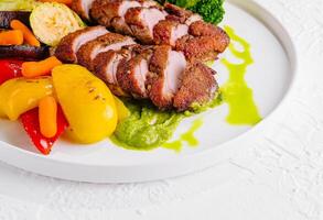 Grilled pork tenderloin with roasted vegetables and sauce photo