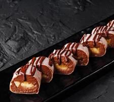 Chocolate drizzled profiteroles on dark plate photo