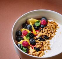 Fresh fruit yogurt bowl on elegant brown background photo