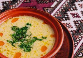 Traditional creamy soup in rustic bowl on patterned textile photo