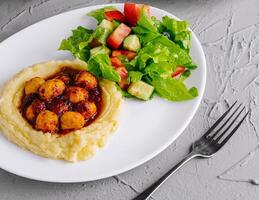 plate of nutritious meals with salad, grilled cutlet, and mashed potatoes on a stone background photo