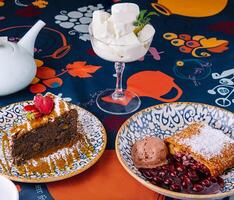 Assorted desserts with ice cream on a colorful tablecloth photo