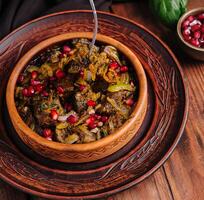 Traditional ceramic bowl with eggplant stew and pomegranate photo