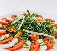 Fresh caprese salad with arugula on white plate photo