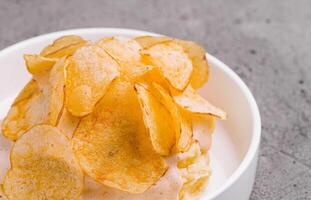 Bowl of crispy golden potato chips photo