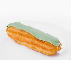 Fresh pistachio eclair on white plate photo