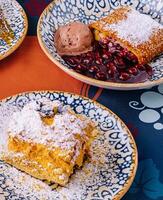 Assorted desserts with ice cream on a colorful tablecloth photo