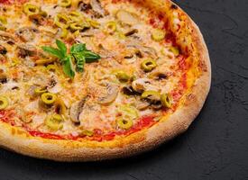 Freshly baked mushroom and olive pizza on black background photo