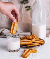 Hand dipping biscuit into milk glass photo