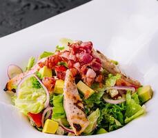 Fresh chicken and bacon salad on modern plate photo