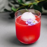 Refreshing watermelon cocktail with ice ball and edible flower photo