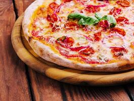 Pizza with basil, red onion and sausage on a wooden board photo