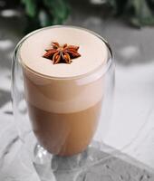 Spiced latte in a transparent glass on textured surface photo