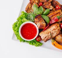 Grilled meat platter with fresh herbs and sauce photo