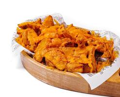 Spicy potato wedges with dip on wooden platter photo