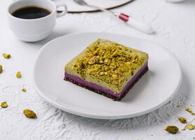 pistacho pastel rebanada con café en un blanco mesa foto