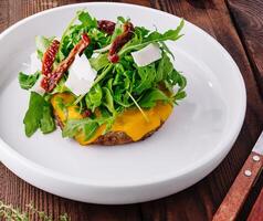 gastrónomo hamburguesa con queso con Rúcula y secado al sol Tomates foto