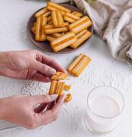 Hands holding churros with milk on table photo