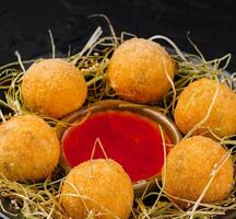 Crispy cheese balls with dip on hay nest photo