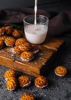 Pouring milk into glass beside freshly baked cookies photo