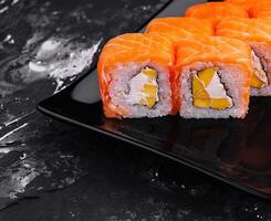 Fresco salmón Sushi rodar en elegante negro plato foto