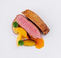 Gourmet duck breast with peach slices on white plate photo