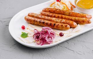 Grilled sausages with sauces and salad on plate photo