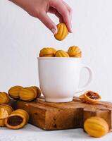 Hand placing a cookie on a cup filled with cookies photo