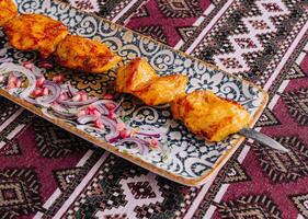 Traditional marinated grilled chicken skewers on ornate plate photo