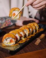 Person holding sushi roll with chopsticks photo