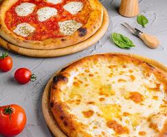 Gourmet margherita and cheese pizzas on rustic table photo