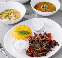 Assorted traditional soups and grilled meat dish on white table photo