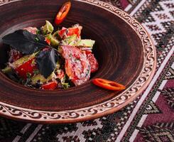 Traditional spicy tomato salad on ethnic pattern tablecloth photo